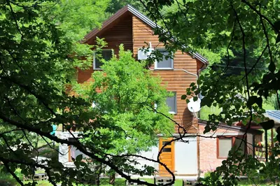 a brown house with trees in front of it at Stone room-Kamena soba in Šipovo