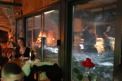 a woman sitting at a table in a restaurant with a fireplace at Stone room-Kamena soba in Šipovo
