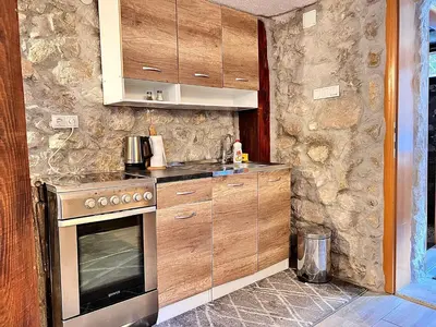 a kitchen with wooden cabinets and a stove top oven at Stone room-Kamena soba in Šipovo