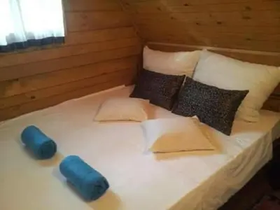 a bed in a cabin with blue pillows at Apartmani Dada Kanjon Grmuša in Bihać
