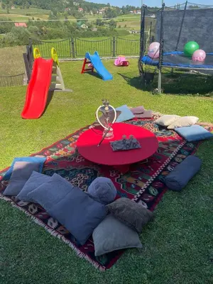 a picnic table on a blanket on the grass with a playground at Villa De Luxe in Bihać