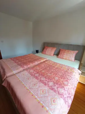 a bedroom with two beds with pink blankets and pillows at Apartman 