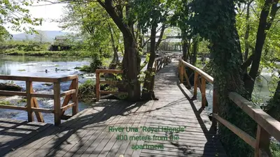 a wooden bridge over a river with trees and water at Apartman 