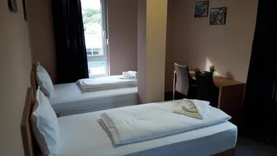 two beds in a room with a window at Apartmani Kakanj in Kakanj