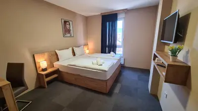 a small bedroom with a bed and a television at Apartmani Kakanj in Kakanj
