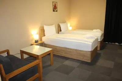a bedroom with two beds and a chair and a table at Apartmani Kakanj in Kakanj