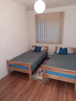 two twin beds in a room with wooden floors at Apartman ALEM Bihac in Bihać