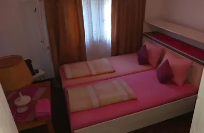 a small bedroom with a bed with pink sheets and pillows at Family house in Visoko