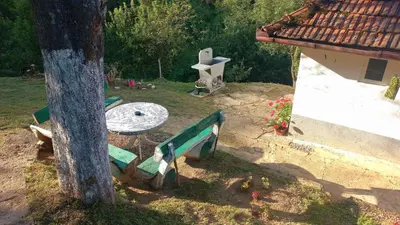 a bench next to a cross next to a tree at Family house in Visoko