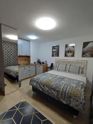 a bedroom with a large bed and a kitchen at Skyline by Nights & Smiles in Tuzla