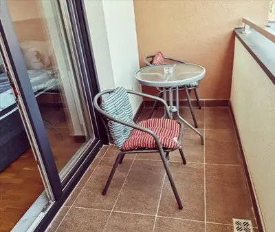a small table and a chair on a balcony at Apartment CITY in Doboj