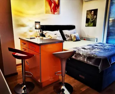 a bedroom with a bed and a bar with two stools at Apartment CITY in Doboj