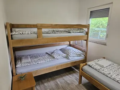 a room with three bunk beds and a table at Villa DIAL Lohovo-dvoslap in Bihać