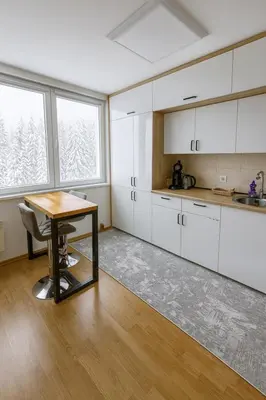a kitchen with white cabinets and a wooden table at Apartman Monti Vlašić in Vlasic