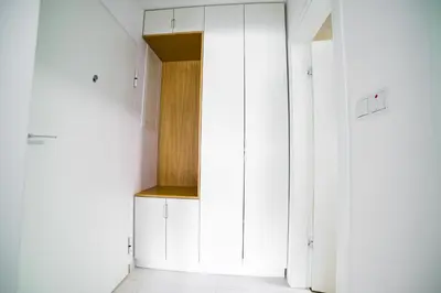 a white kitchen with white cabinets and a wooden door at Sun Square Apartments in Tuzla