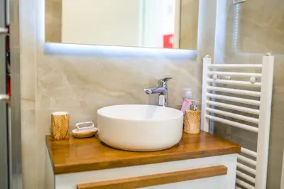 a bathroom with a white sink on a wooden counter at Sun Square Apartments in Tuzla