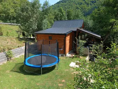 a small house with a trampoline in the yard at Cottage Auto Camp Vinac in Jajce