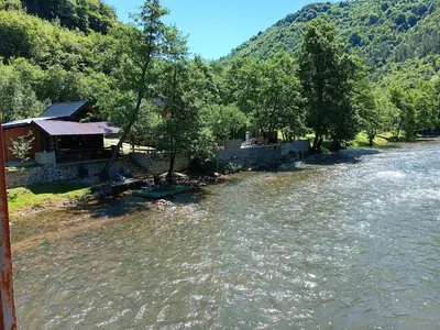 a river with a building in the middle of it at Cottage Auto Camp Vinac in Jajce