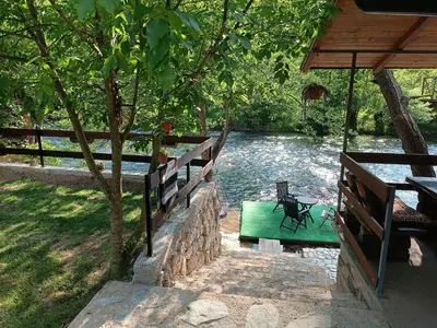 a green bench sitting next to a river at Cottage Auto Camp Vinac in Jajce