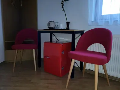 two red chairs and a table with a red refrigerator at Prenoćište Slapovi in Jajce