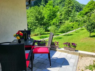 a patio with a table and chairs and flowers at Prenoćište Slapovi in Jajce