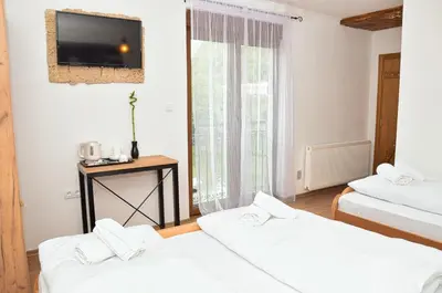 a room with two beds and a tv on the wall at Prenoćište Slapovi in Jajce