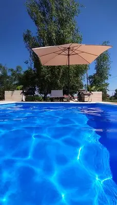 a large swimming pool with an umbrella and a table at Apartman Brezuljak Banja Luka Cokorska polja in Macanovići