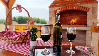 two glasses of red wine on a table with a fireplace at Apartman Brezuljak Banja Luka Cokorska polja in Macanovići