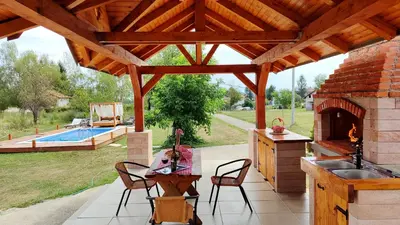 a wooden pavilion with a fireplace and a pool at Apartman Brezuljak Banja Luka Cokorska polja in Macanovići