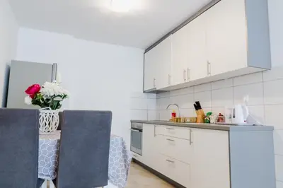 a kitchen with white cabinets and a vase of flowers at Apartment Andrej in Tomislavgrad