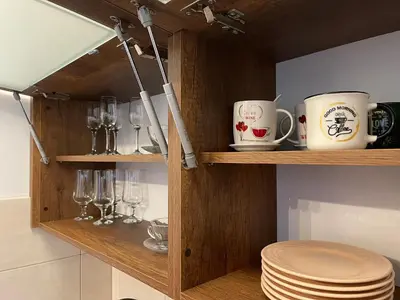 a wooden shelf with cups and glasses and plates at Prestige Apartment Teslic in Teslić