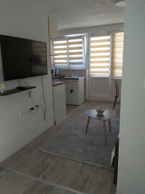 a living room with a flat screen tv and a table at Apartman Alma in Bihać