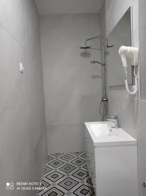 a white bathroom with a sink and a shower at Mars in Banja Luka