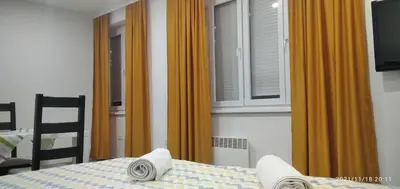 a bedroom with a bed and a window with orange curtains at Mars in Banja Luka