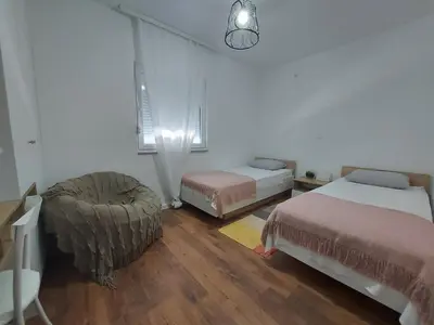 a bedroom with two beds and a chair in it at Little Aria in Ripač