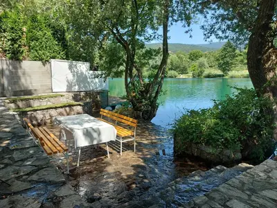 a table and two chairs sitting next to a lake at Little Aria in Ripač