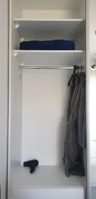 a closet with white shelves and a blue pillow and a bag at Apartman Alina Comfort in Banja Luka