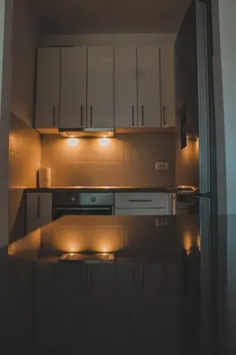 a kitchen with white cabinets and lights in it at Apartman Alina Comfort in Banja Luka