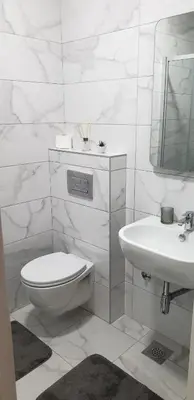 a white bathroom with a toilet and a sink at Apartman Alina Comfort in Banja Luka
