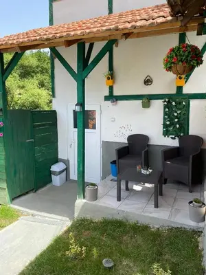 a patio with two chairs and a building with a green door at Bazeni-Etno selo u Visokom in Visoko