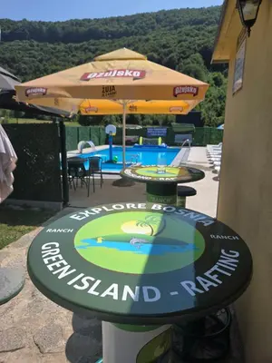 a sign for a restaurant with a table and an umbrella at Vikendica, Bazen, Šedrvan, Rafting na Uni, Quad in Bihać