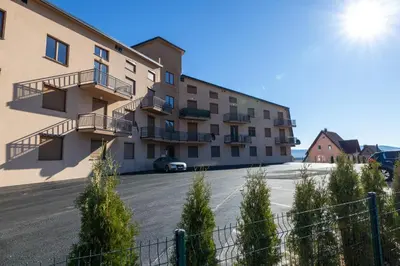 a building with a parking lot in front of it at Apartman Kupres Ski in Kupres