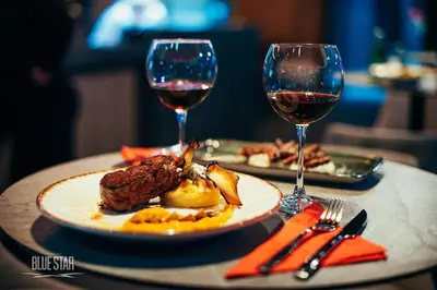 a table with a plate of food and two glasses of wine at Motel BTG in Tomislavgrad