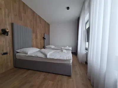 a bedroom with a bed with white sheets and wooden floors at Motel BTG in Tomislavgrad