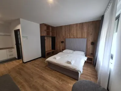 a bedroom with a white bed and wooden floors at Motel BTG in Tomislavgrad