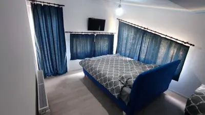 a bedroom with a blue bed and blue curtains at Beverly Hills SPA Pool House in Donji Podgradci