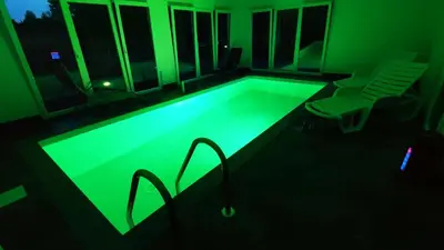 a pool with green lighting in a dark room at Beverly Hills SPA Pool House in Donji Podgradci