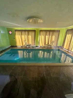 a swimming pool with two chairs in the middle at Beverly Hills SPA Pool House in Donji Podgradci