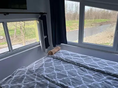 a bedroom with two windows and a bed with a comforter at Beverly Hills SPA Pool House in Donji Podgradci