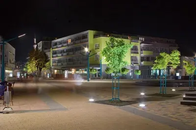 a city street at night with a building and trees at COZY CENTER Apartment Bihać in Bihać